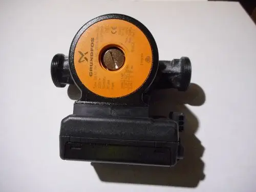 Schwarze Pumpe mit orangefarbenem Deckel und Anschlussstutzen, versehen mit einer Marke, die den Namen Remeha beinhaltet. Das Gerät ist in einfacher Ansicht auf einem hellen Untergrund montiert.